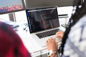 A developer coding at a laptop with lines of codes on the screen